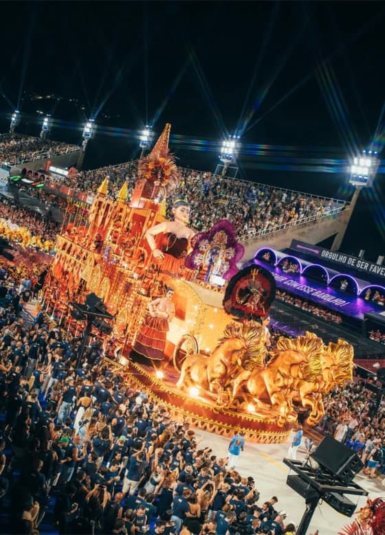 Desfile de Carnaval iluminado com público acompanhando o cortejo